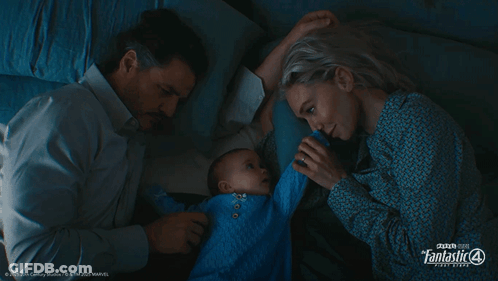 A Man And A Woman Laying Next To A Baby With Fantastic 4 Written On The Bottom Left GIF
