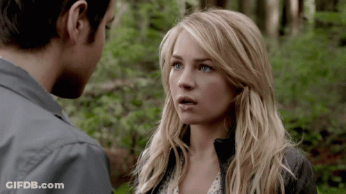 A Man And A Woman Looking At Each Other In The Woods GIF