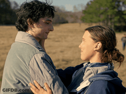 A Man And A Woman Looking Into Each Other 'S Eyes In A Field GIF