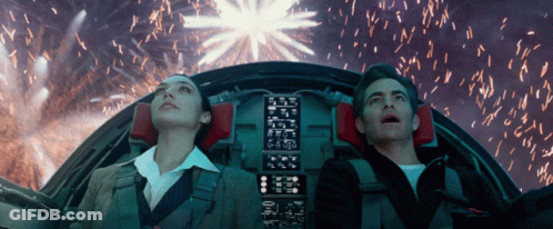 A Man And A Woman Looking Up At Fireworks In A Cockpit GIF