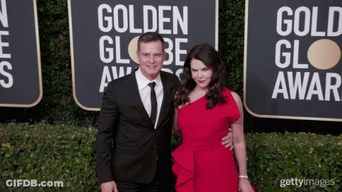 A Man And A Woman Pose On The Red Carpet At The Golden Globe Award GIF