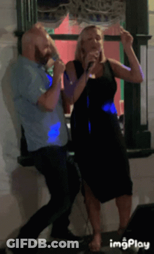 A Man And A Woman Singing Into Microphones In Front Of A Window With Imgplay At The Bottom GIF