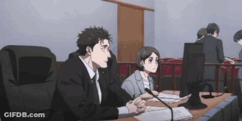 A Man And A Woman Sit At A Desk In Front Of A Computer GIF