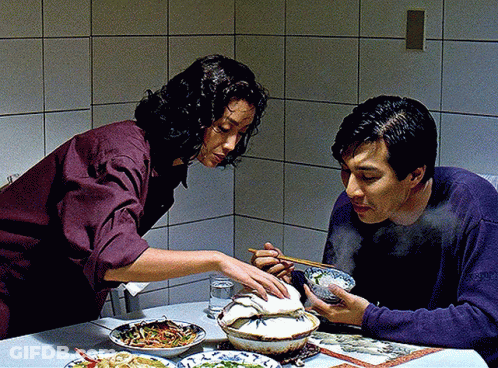 A Man And A Woman Sit At A Table Eating Food GIF