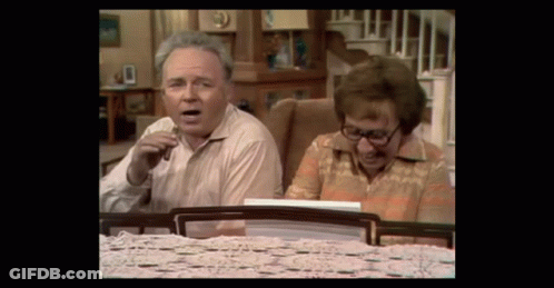 Man And Woman Sitting At Table Looking At Something GIF