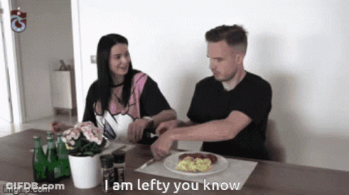 A Man And A Woman Sit At A Table With A Plate Of Food And The Words I Am Lefty You Know On The Table GIF