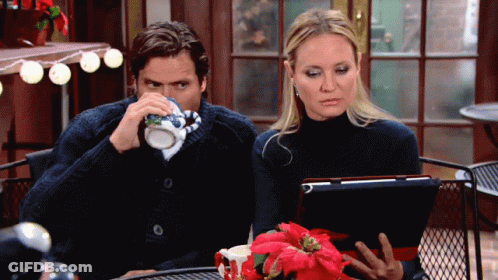 A Man And A Woman Sit At A Table With A Tablet GIF