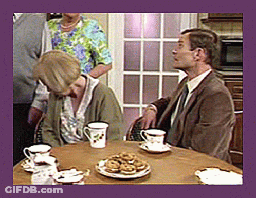 A Man And A Woman Sit At A Table With Cups And Saucers Of Tea GIF