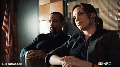 A Man And A Woman Sit At A Table With The Nbc Logo Visible GIF