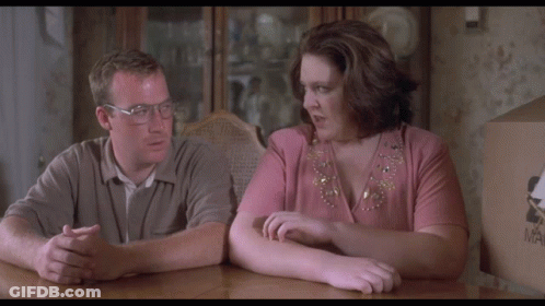 A Man And A Woman Sit At A Table With The Words " I Want That " On The Screen GIF