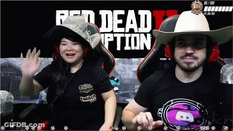A Man And A Woman Sit In Front Of A Red Dead Redemption Screen GIF