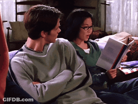 A Man And A Woman Sit On A Couch Reading Books GIF