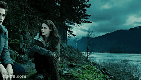 A Man And A Woman Sit On A Rock By A Lake GIF