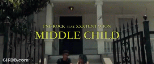A Man And A Woman Sit On The Steps Of A House With The Words Middle Child Written Above Them GIF