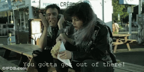 A Man And A Woman Sitting At A Picnic Table With The Words You Gotta Get Out Of There On The Bottom GIF