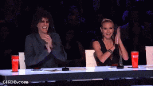 A Man And A Woman Sitting At A Table Clapping GIF