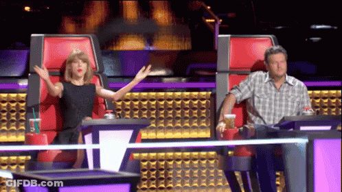 A Man And A Woman Sitting In Red Chairs With Their Arms Outstretched GIF