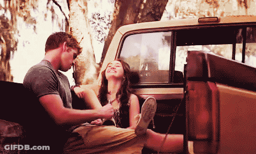 A Man And A Woman Sitting In The Back Of A Truck GIF