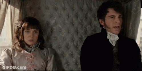 A Man And A Woman Sitting Next To Each Other In A Room GIF