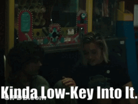 A Man And A Woman Sitting Next To Each Other With Kinda Low-Key Into It Written On The Bottom GIF