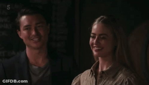 A Man And A Woman Sitting Next To Each Other With The Number 5 On The Bottom Left GIF