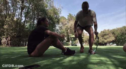 A Man And A Woman Sitting On The Grass Talking GIF