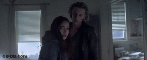A Man And A Woman Standing In A Dark Room GIF
