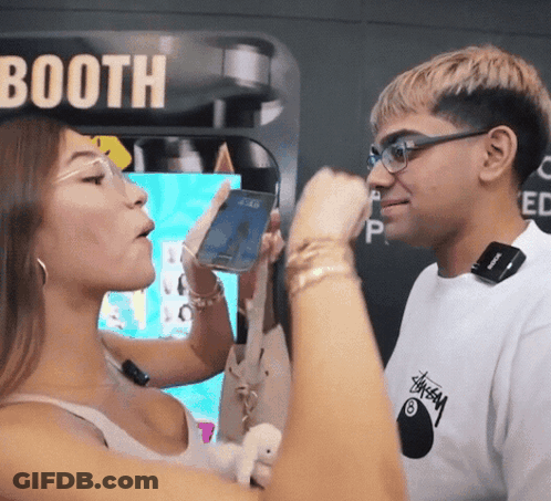 A Man And A Woman Standing In Front Of A Booth GIF