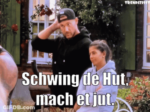 A Man And A Woman Standing In Front Of A House With Schwing De Hut Mach Et Jut Written On The Screen GIF