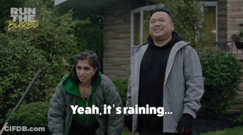 A Man And A Woman Standing In Front Of A House With Yeah It 'S Raining Written Below Them GIF