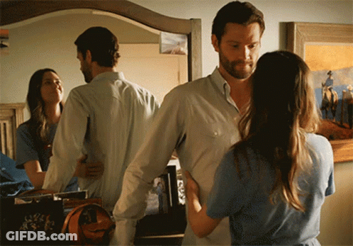 A Man And A Woman Standing In Front Of A Mirror GIF