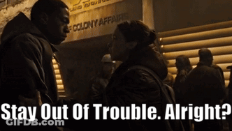 A Man And A Woman Standing In Front Of A Sign That Says " Stay Out Of Trouble Alright " GIF