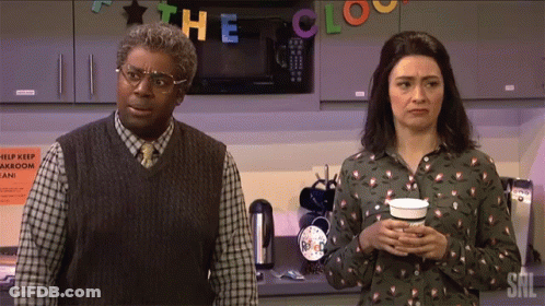 A Man And A Woman Standing In Front Of A Sign That Says The Clock On It GIF