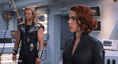 A Man And A Woman Standing Next To Each Other In A Room GIF