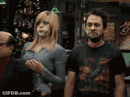 A Man And A Woman Standing Next To Each Other In Front Of A Bar GIF