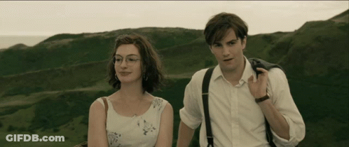 A Man And A Woman Standing Next To Each Other In Front Of A Mountain GIF