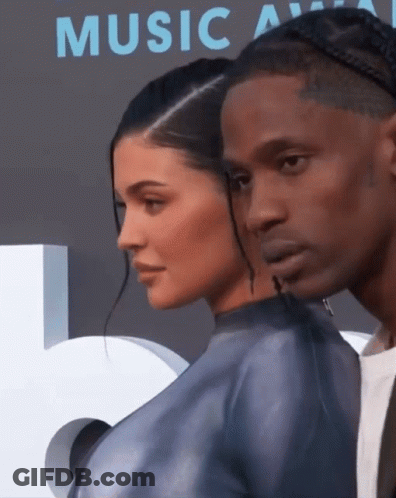 A Man And A Woman Standing Next To Each Other In Front Of A Music Awards Sign GIF