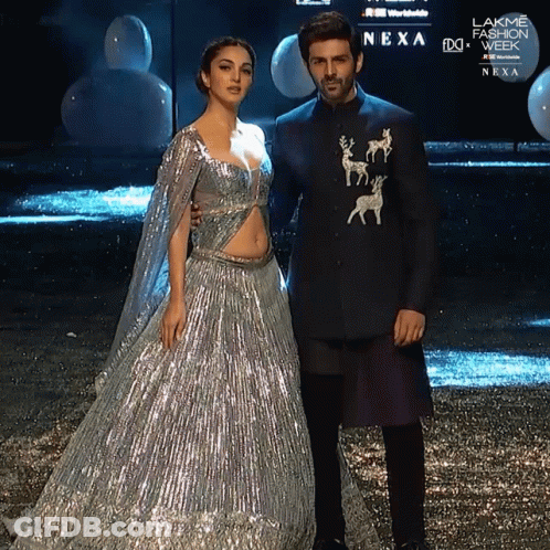 A Man And A Woman Standing Next To Each Other In Front Of A Sign That Says Nexa On It GIF