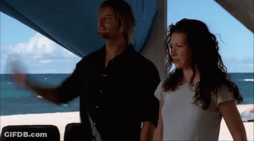 A Man And A Woman Standing Next To Each Other On The Beach GIF