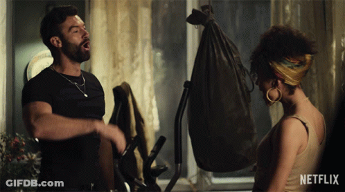 A Man And A Woman Standing Next To Each Other With A Netflix Logo In The Corner GIF