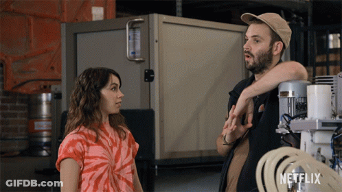 Man And Woman Standing Next To Netflix Logo GIF