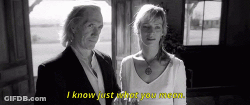 A Man And A Woman Standing Next To Each Other With I Know Just What You Mean Written In Yellow GIF