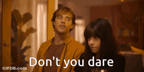 A Man And A Woman Standing Next To Each Other With The Words " Do N't You Dare " Written On The Screen GIF