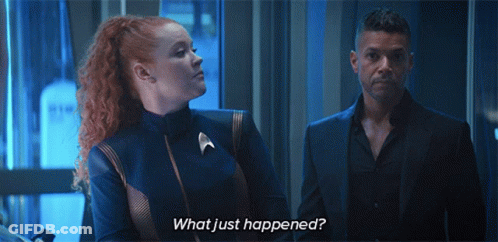 A Man And A Woman Standing Next To Each Other With The Words What Just Happened Written On The Bottom GIF