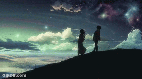 A Man And A Woman Standing On Top Of A Hill Holding Hands GIF