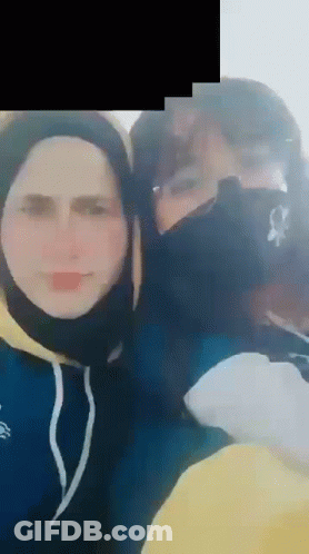 A Man And A Woman Wearing Face Masks Are Posing For A Picture Together . GIF