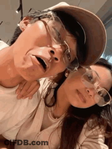 A Man And A Woman Wearing Glasses Are Posing For A Picture Together . GIF
