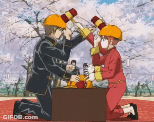 A Man And A Woman Wearing Hard Hats Are Holding Hammers GIF
