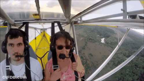 A Man And A Woman Wearing Headphones Are Flying A Small Plane GIF