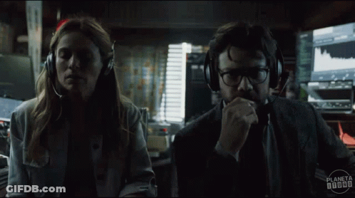 A Man And A Woman Wearing Headphones Are Looking At Each Other In A Dark Room . GIF